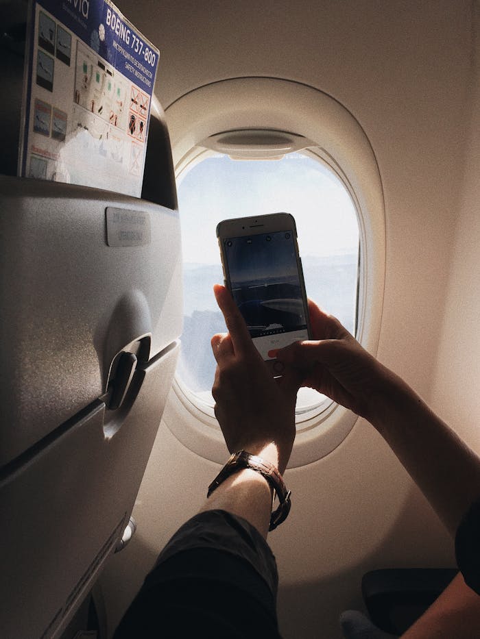 A traveler takes a photo of the aerial view from an airplane window, capturing the essence of in-flight travel.